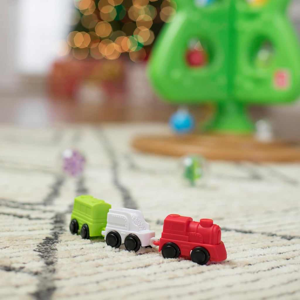 Grüner interaktiver Weihnachtsbaum mit bunten Spielelementen und kleiner Spielzeugeisenbahn