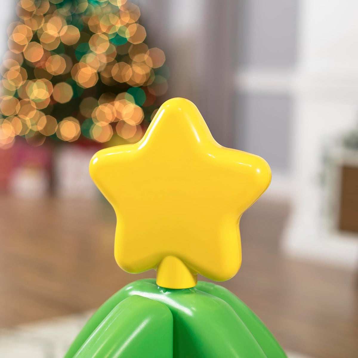 Grüner interaktiver Weihnachtsbaum mit bunten Spielelementen und kleiner Spielzeugeisenbahn