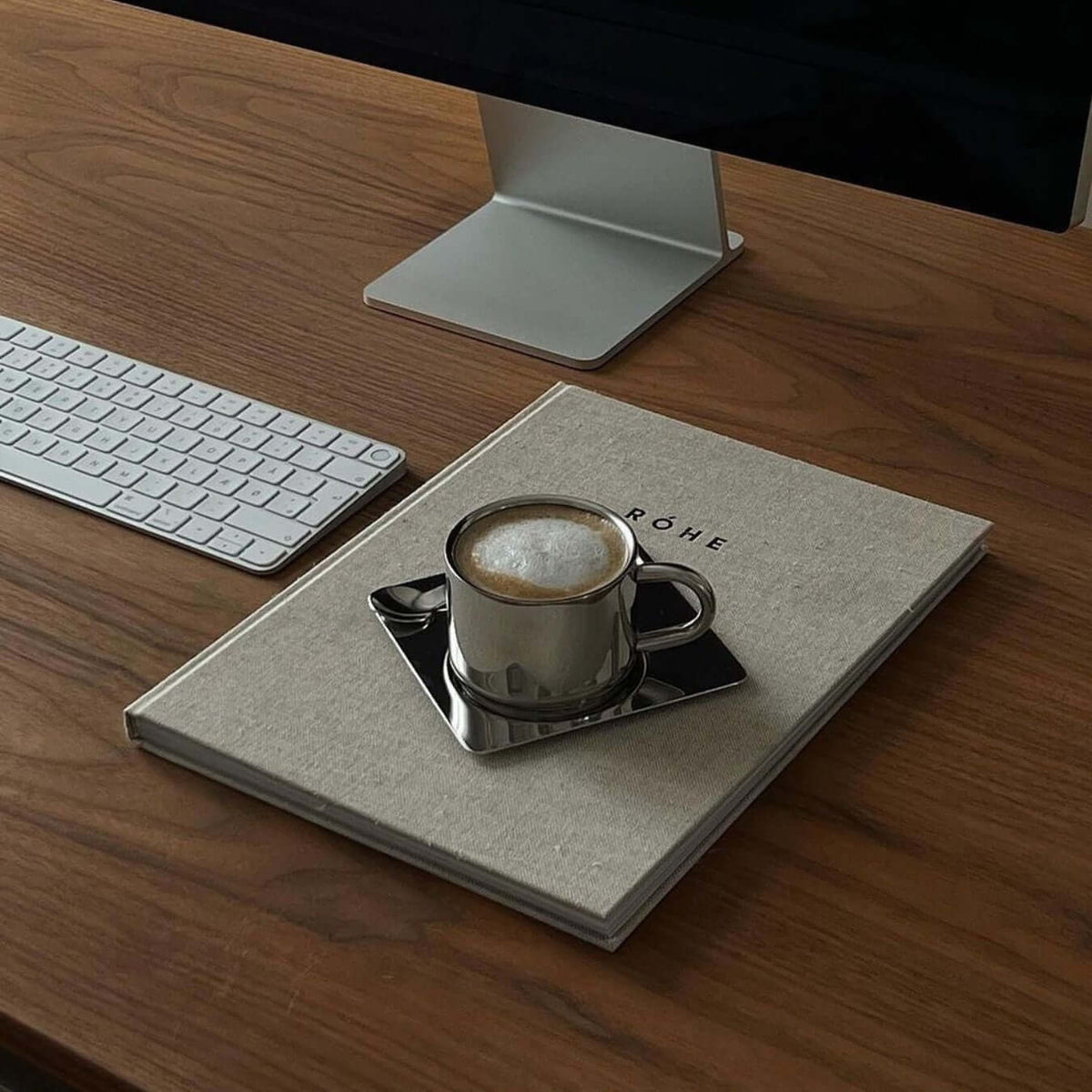 Silberfarbene Tasse mit Untertasse und Löffel in spiegelnder Optik
