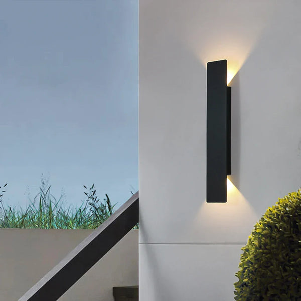 Schwarze vertikale LED-Außenwandleuchte mit warmweißem Licht an einer Fassade