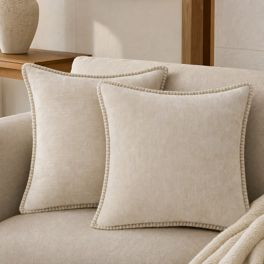 Quadratisches Zierkissen mit weicher Oberfläche und dekorativer Kantenborte auf einem Sofa