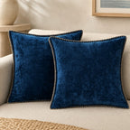Quadratisches Zierkissen mit weicher Oberfläche und dekorativer Kantenborte auf einem Sofa