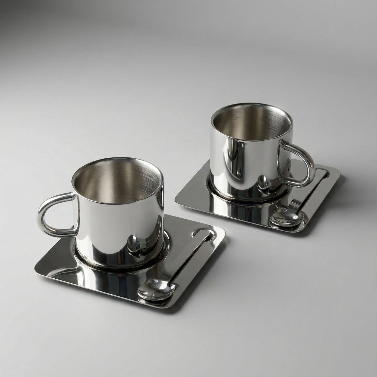 Silberfarbene Tasse mit Untertasse und Löffel in spiegelnder Optik