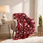 Rote Fleecedecke mit weißem Schneeflockenmotiv über einem Sessel