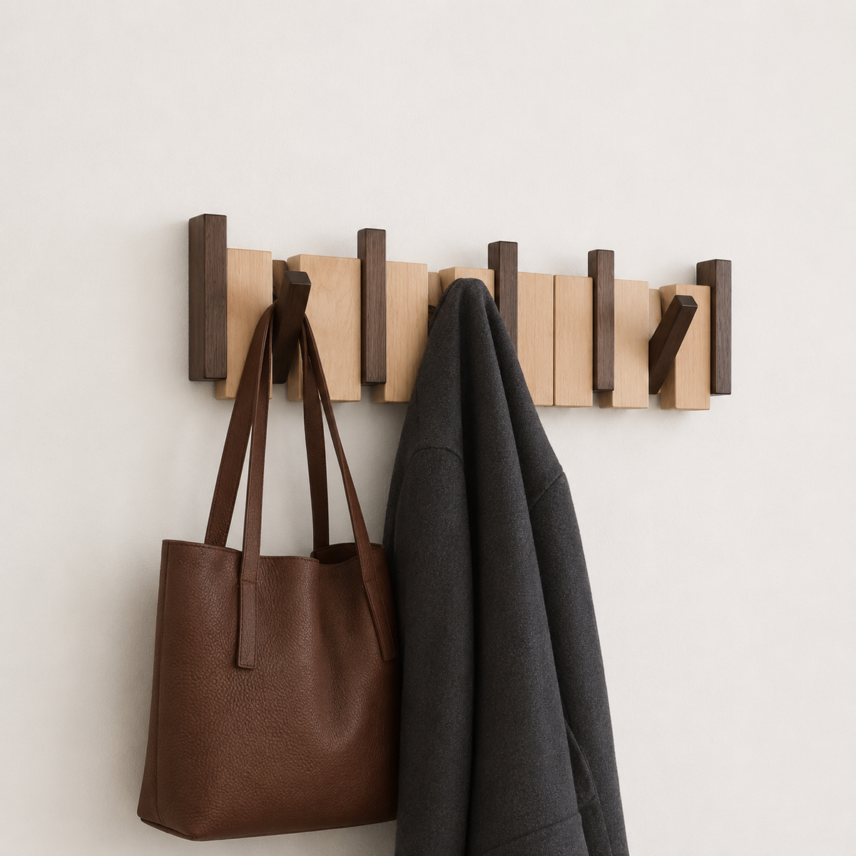 Wandgarderobe aus Holz mit mehreren Klapphaken in hellen und dunklen Holztönen