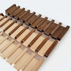 Wandgarderobe aus Holz mit mehreren Klapphaken in hellen und dunklen Holztönen